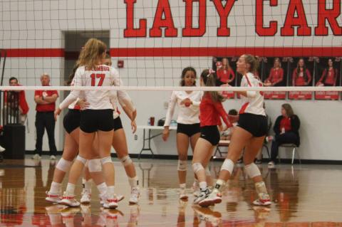 Lady Cardinals celebrate after Taylor Morrow earns the team a point with a kill. Photo by Evan Hale 